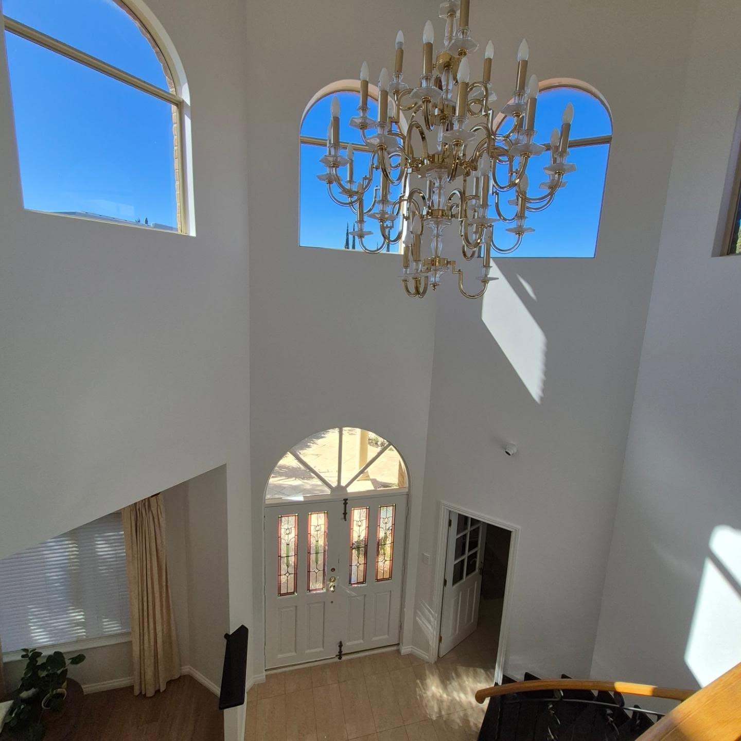 Freshly painted double-height entrance with arched windows and chandelier